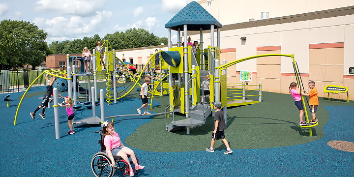Children playing on a playground with a girl in a wheelchair in the foreground.