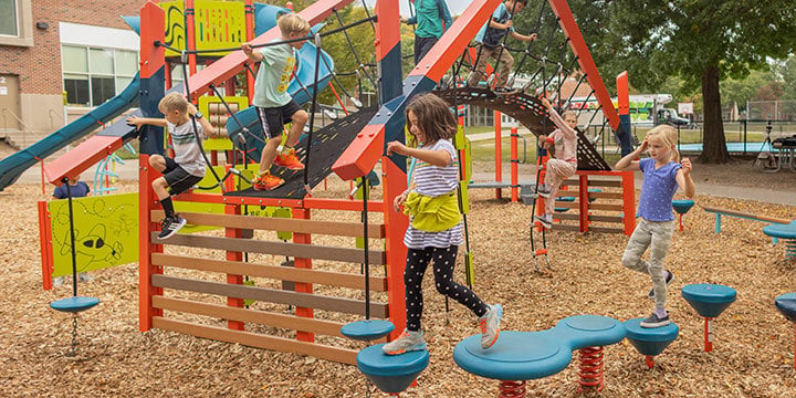 Kids playing on an orange FORMA play structure 