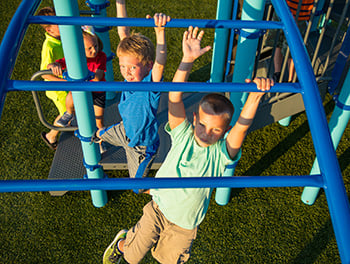 Overhead view of two boys swinging on monkey bars