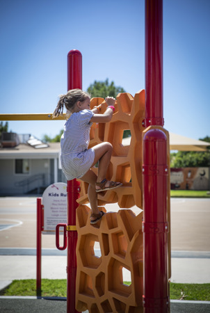 A child climbs on a geometric-shaped playground climber. 