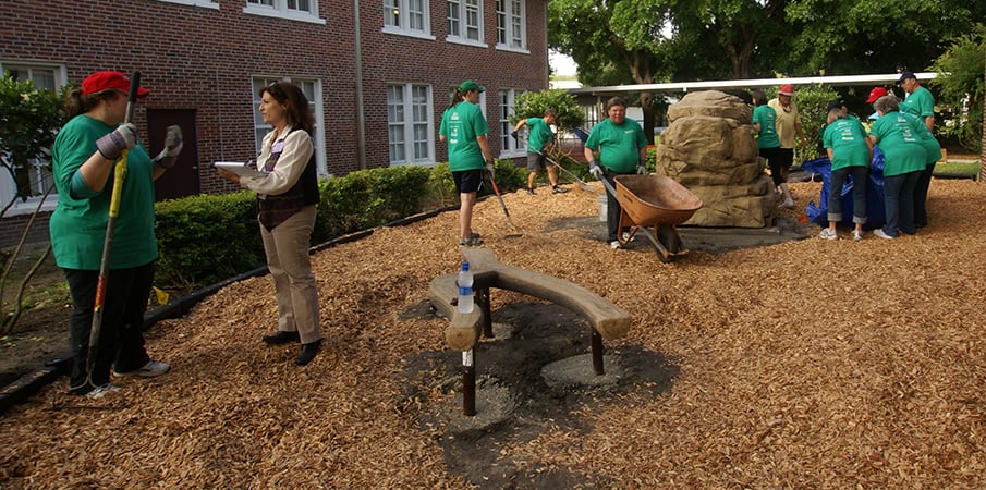 Volunteers working together to build make a nature-inspired playground.