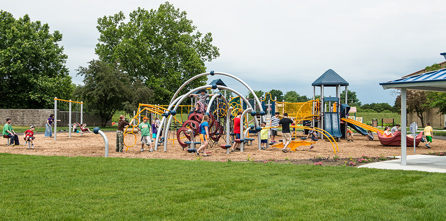 Children playing on a Evos and PlayBooster playground sets.