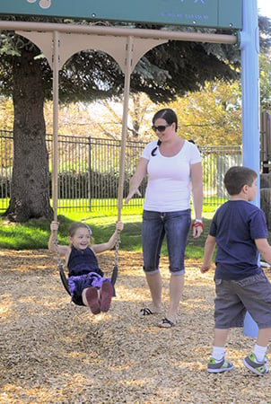 A woman pushes a little girl on a swing. 