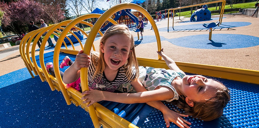 Two girls smile as they play on a Roller Table.