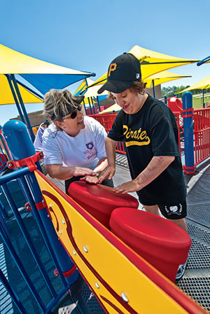 A young person plays the bongo drums on the bongo panel, which is a component that promotes playground accessibility. 